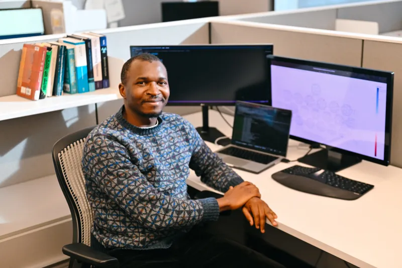 Scientist in a sweater sitting at a computer
